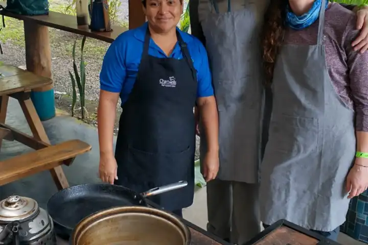 a group of people standing near a pan of food