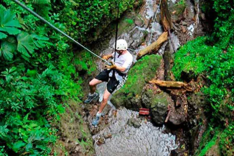 man being lowered while canyoning in the jungle