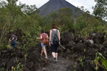 people walking in jungle landscape with volcano in distance