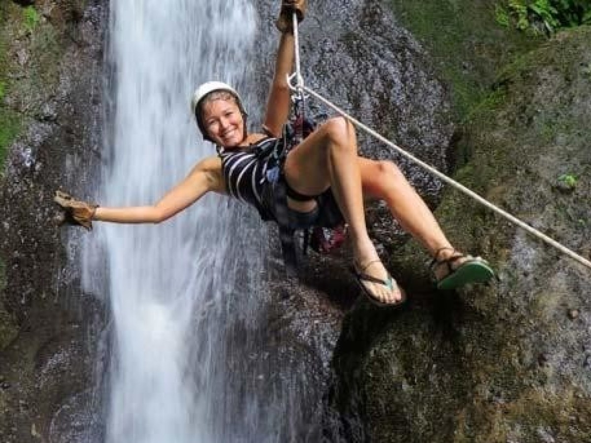 woman ziplining before a waterfall