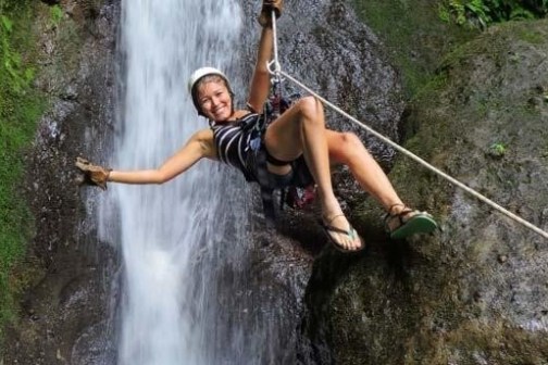 woman ziplining before a waterfall