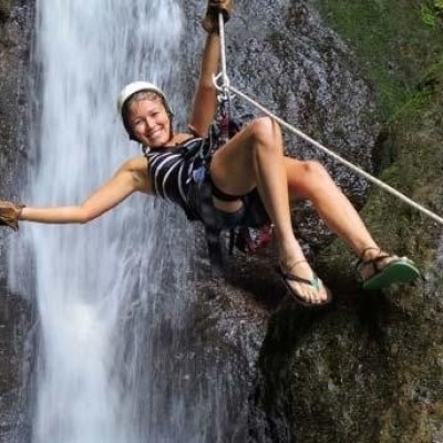 woman ziplining before a waterfall